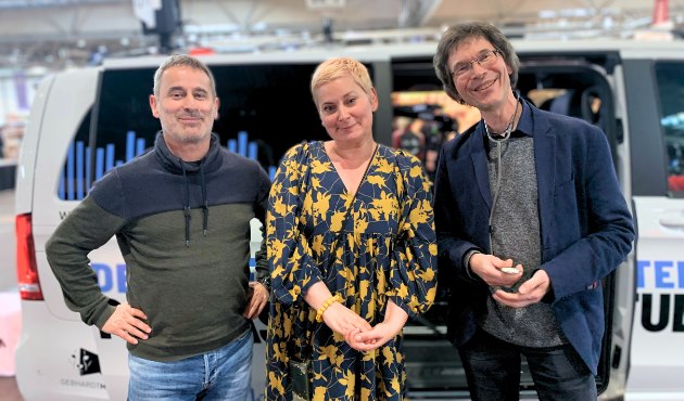 Ralf Schweikart, Tamara Bach und Stefan Hauck stehen lachend vor dem Podcast-Bus