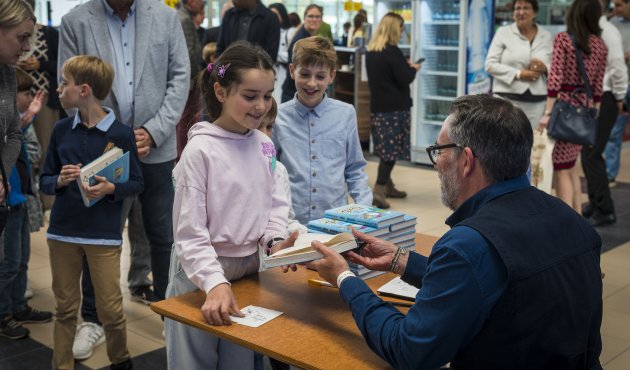 Kinder und Eltern stehen Schlange bei Preisträger Adam Stower beim Signieren