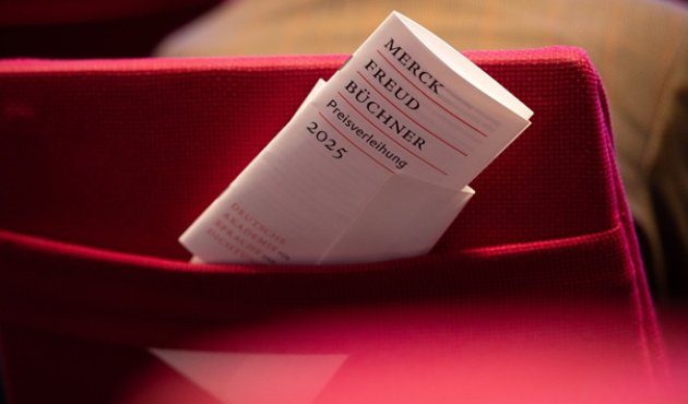 Das Programmheft, in die Lehne eines roten Klappsitzes gesteckt