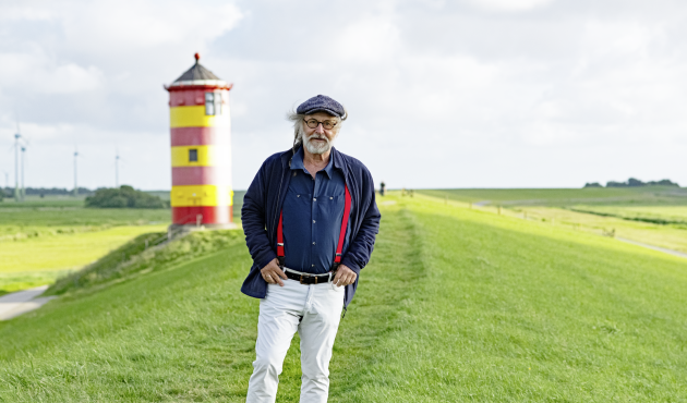 Foto von Klaus-Peter Wolf auf einem Deich vor einem Leuchtturm
