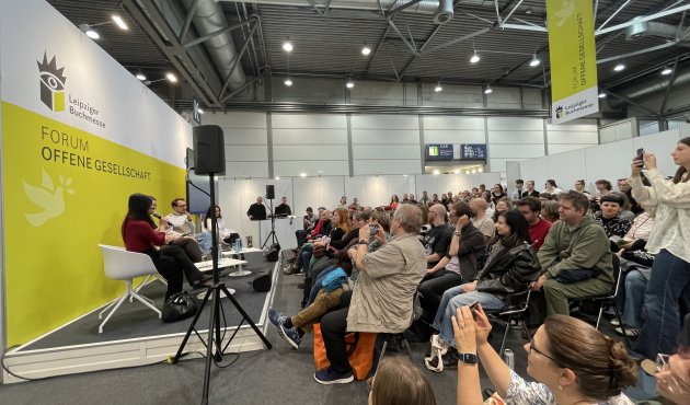 Podium, davor sehr viele Zuhörer:innen