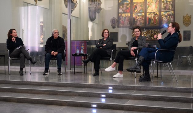 Vier Personen sitzen im Gespräch im Altarraum der kirche