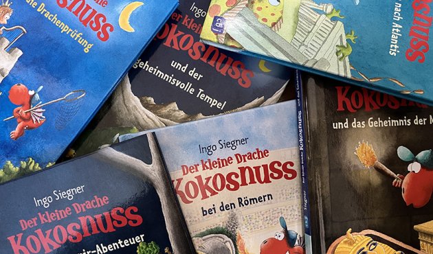 Viele Ausgaben von "Der kleine Drache Kokosnuss" liegen übereinander