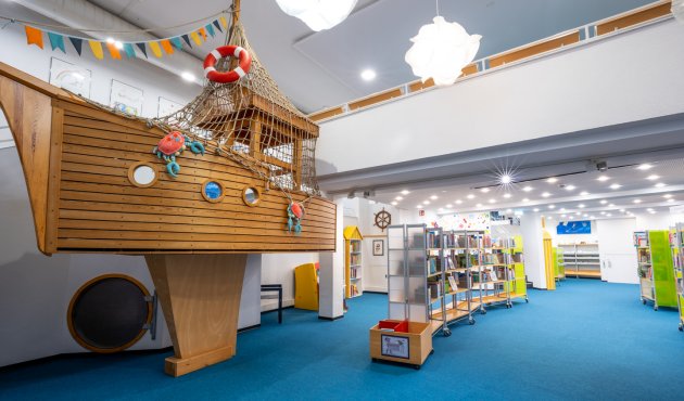 helle, moderne Kinderabteilung in der Bibliothek, mit Bücherregale und einem Schiff zum Hineinklettern 