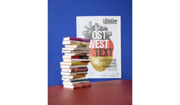 Ein Bücherturm vor dem Plakat des Festivals