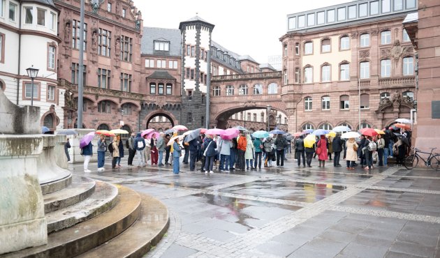 Eine lange Schlange mit Regenschirmen vor der Paulskirche