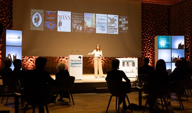 Moderatorin Katty Salié zeigt auf die 8 Buchcover der nominierten Titel