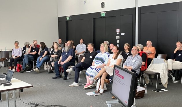 Blick auf die Zuhörerinnen und Zuhörer, die auf Stühlen sitzen