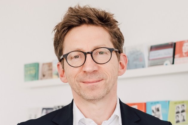 Johannes Stricker im Verlag vor einem Regal mit Hörbüchern 