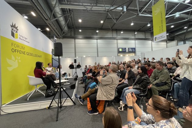 Podium, davor sehr viele Zuhörer:innen