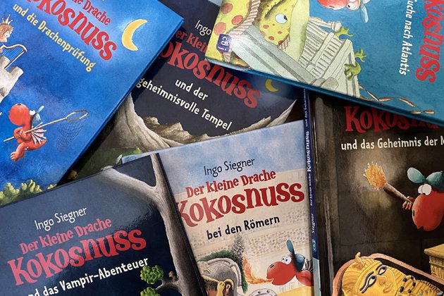 Viele Ausgaben von "Der kleine Drache Kokosnuss" liegen übereinander