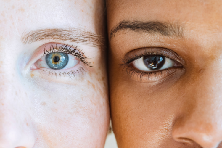 Nahaufnahme von zwei Frauengesichtern: eins mit dunkler und eins mit heller Hautfarbe