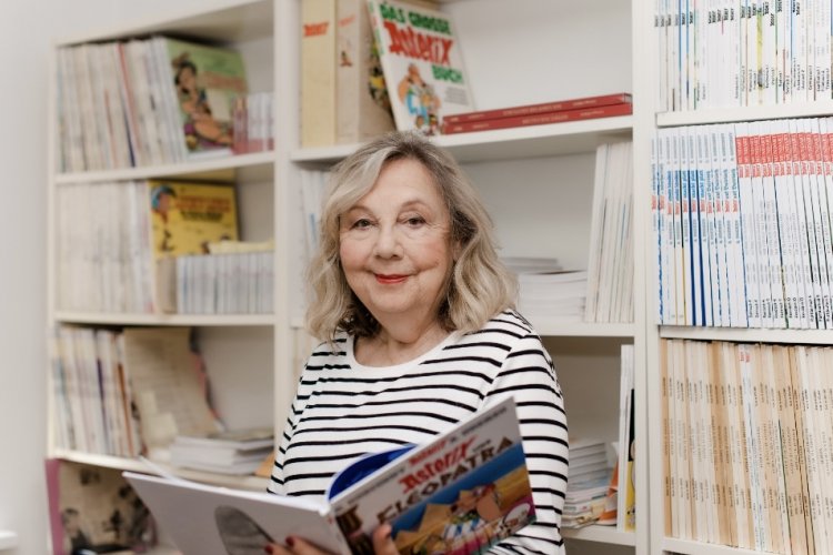 Gudrun Penndorf mit Ringelpulli und Asterix-Band in den Händen vor Bücherregal