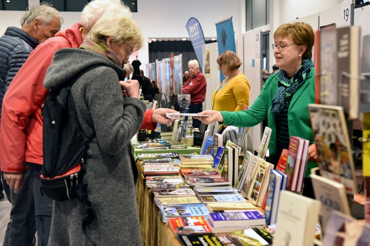 Bei den Thüringer Buchtage 2023 reicht eine Verlegerin Besucher:innen Bücher