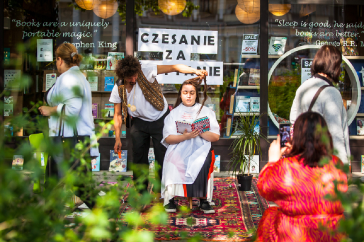 Danny Beuerbach schneidet vor einem Buchladen einer Frau die Haare