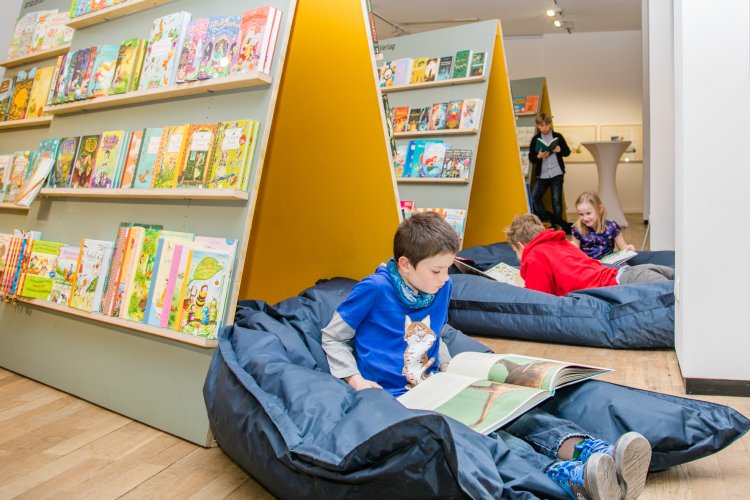 Kinder lesen in Sitzsäcken vor Bücherregalen