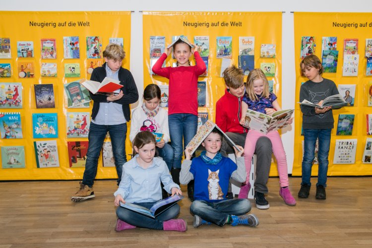Kinder mit Büchern vor gelbem Vorhang