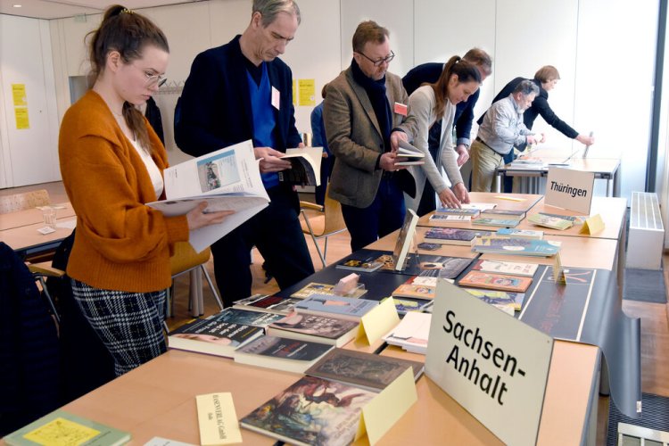 Besucher schauen Bücher an beim Pressegespräch der Verlage aus SaSaThü