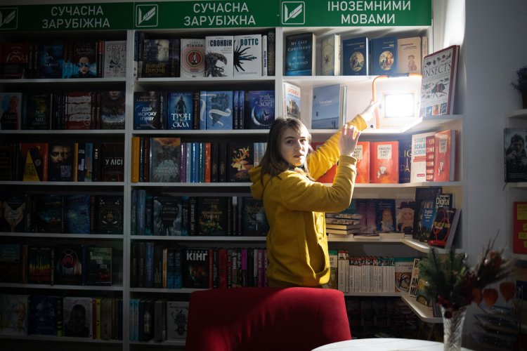 Buchhändlerin Galina stellt während eines Stromausfalls batteriebetriebene Lampen in die Regale der Buchhandlung Vivet in Charkiw. 