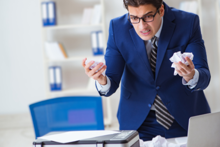 Mann im Anzug verzweifelt vor Drucker