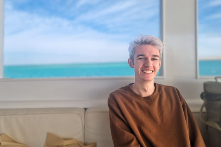 David Michalik vor einem Fenster mit Meerblick