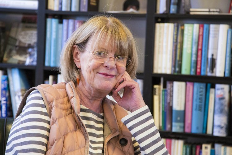 Porträt von der lächelnden Ida Schöffling, die vor einem Bücherregal sitzt