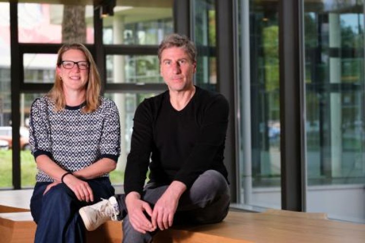 Christina Pick und Hannes Frisch sitzen nebeneinander vor einer Glasfront im Verlagsgebäude