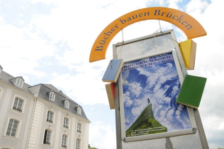 Plakat und Schriftzug vor Himmel