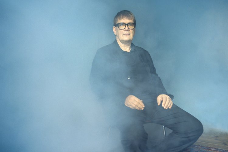 Sven Regener sitzt und schaut in die Kamera