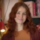 Jana Brammer steht lächeln vor einem Bücherregal mit einer Lampe