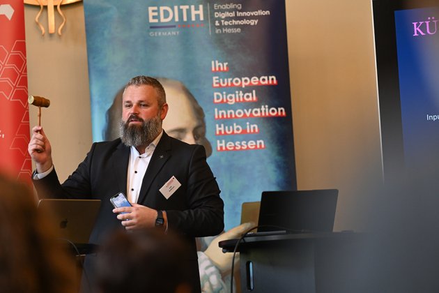 Felix Broßmann ist Partner bei der SKAD AG, einer Unternehmensberatung, bei einem Vortrag mit Hammer und Handy in der Hand