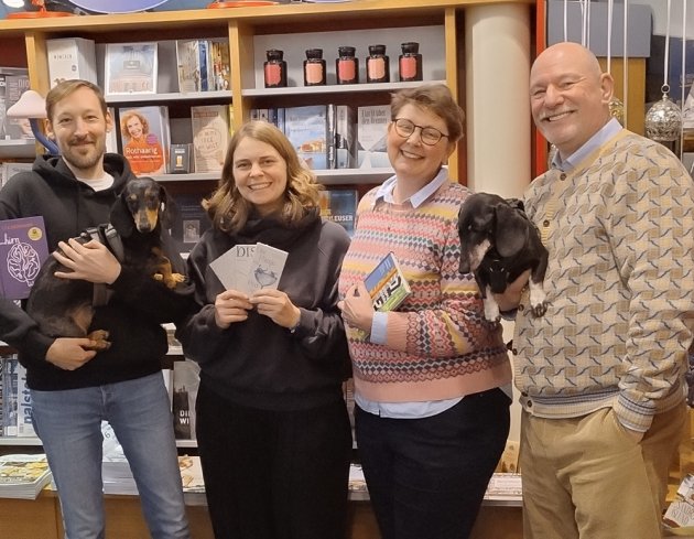 Vier Personen in der Buchhandlung, zwei davon tragen Dackel auf dem Arm
