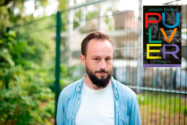 Johann Reißer steht im Freien vor einem grünen Metallzaun, neben ihm ist das Cover seines Buches zu sehen