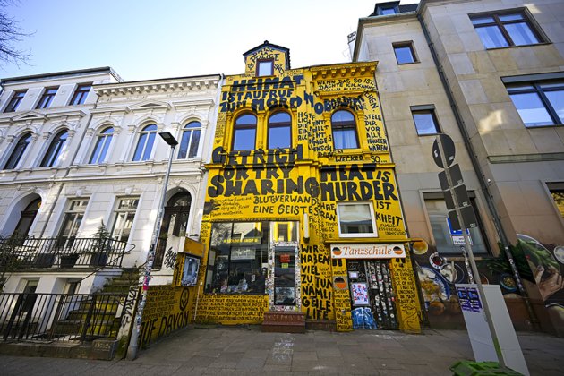 Außenansicht der Buchhandlung Golden Shop in Bremen: politische Graffitis auf gelber Wand