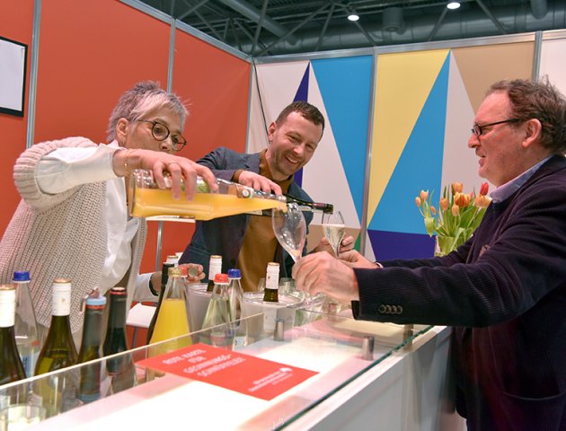 Börsenvereinsvorsteher Sebastian Guggolz und Karin Schmidt-Friderichs schenken einem Gast Sekt und Osaft ein