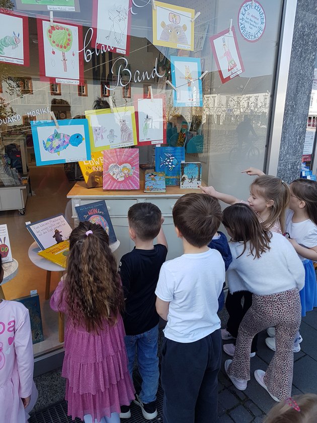 Kinder schauen ins Schaufenster, wo ihre Bilder hängen