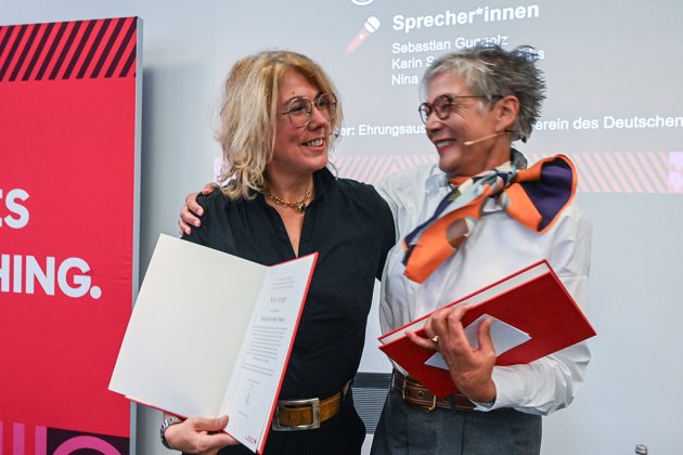 zwei Frauen mit Urkunden umarmen sich