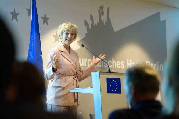 Renate Nikolay spricht stehend am Rednerpult mit einer Europaflagge im Hintergrund