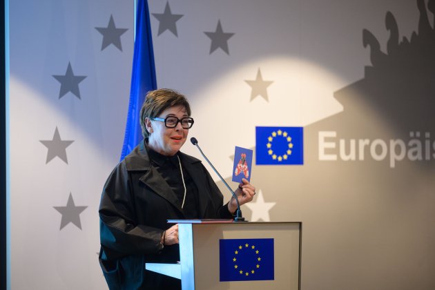 Halbtotale von Katharina Uppenbrink am Stehpult. Im Hintergrund und am Pult die europäischer Flagge