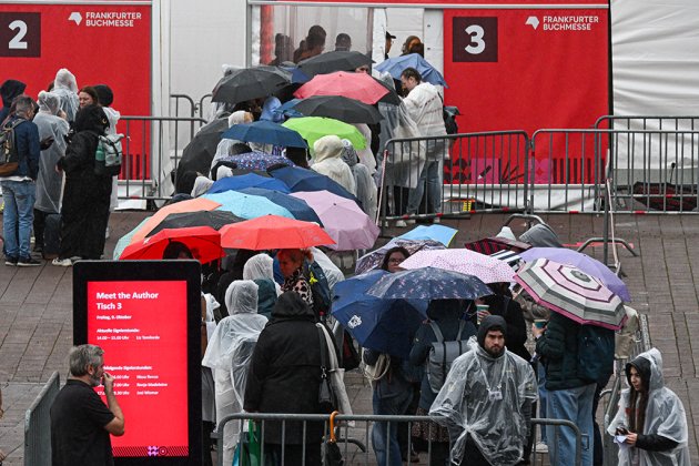 Warteschlange unter bunten Regenschirmen