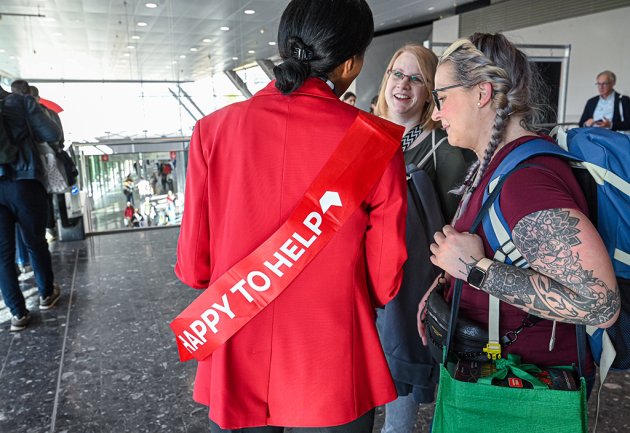 Messehostess mit roter "Hapy to help"-Banderole