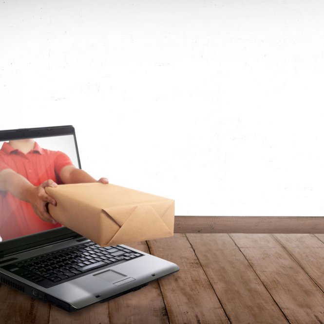 E-Commerce: Ein Päckchen wird aus einem Laptop heraus gereicht