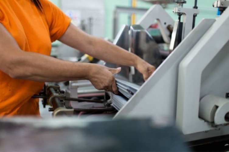 Detailaufnahme: Ein Mann arbeitet an einer modernen Druckerpresse