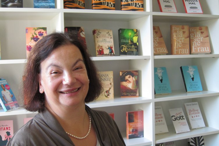 Christine Steffen-Reimann lächelnd vor einem Bücherregal