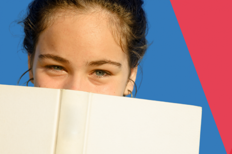 Eine junge Frau versteckt den unteren Teil ihres Gesichts hinter einem Buch
