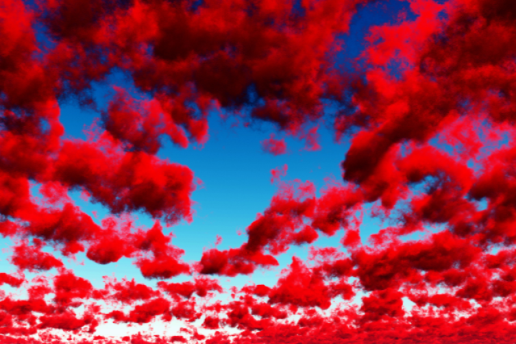 Rote Wolken ziehen über einen blauen Himmel
