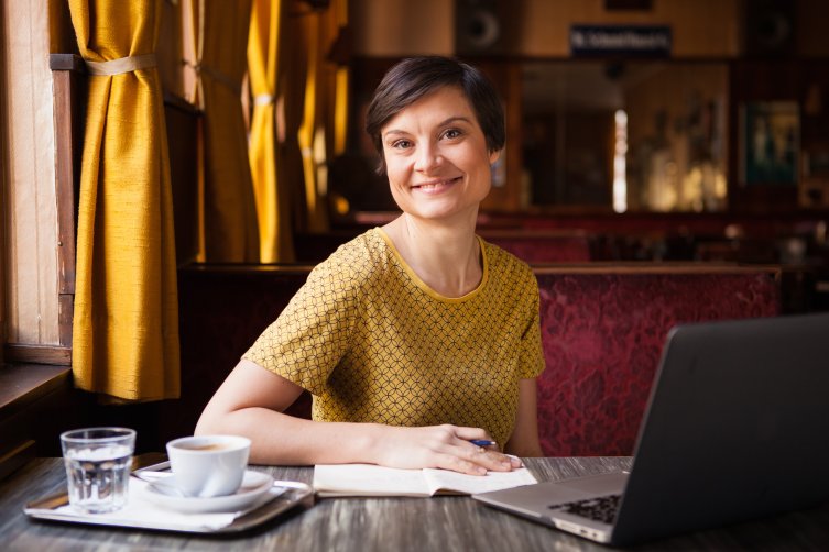 Lena Raubaum im Cafe mit Laptop und Buch