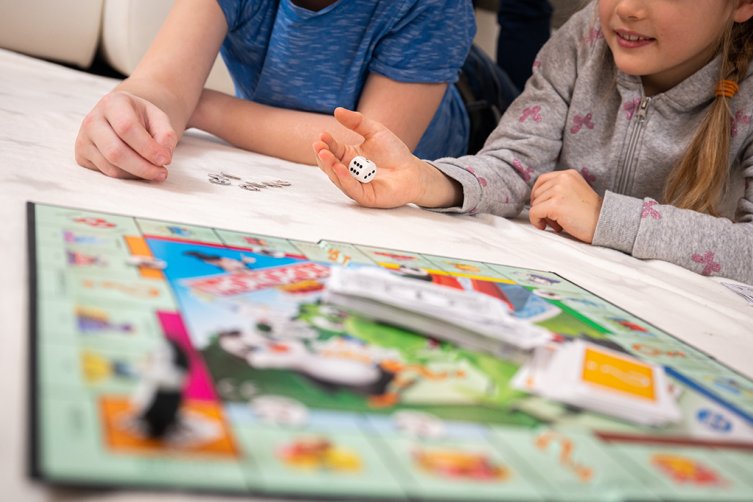 Kinder liegen auf dem Boden und spielen ein Brettspiel