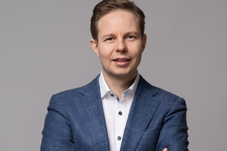 Porträt von Claudio Di Vincenzo im Anzug vor grauem Hintergrund